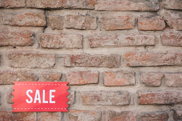 Free photo red sale tablet on brick wall