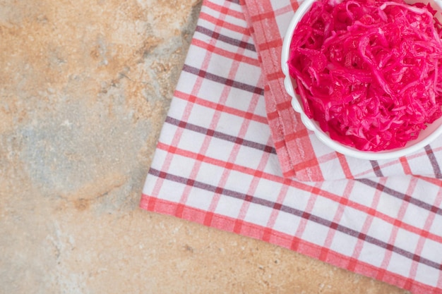 Red sauerkraut salad in white bowl with tablecloth