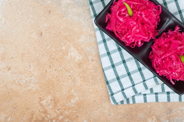 Red sauerkraut salads on black plate with tablecloth