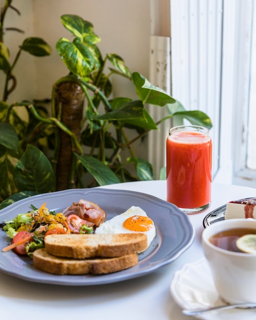 Free photo red smoothie; breakfast and tea on white table near the epipremnum aureum plant