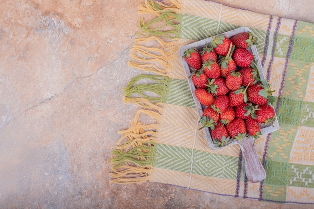 Free photo red strawberries in a rustic wooden platter on the marble