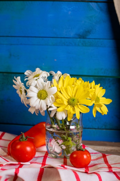 Free photo red tomatoes and a flower vase on blue