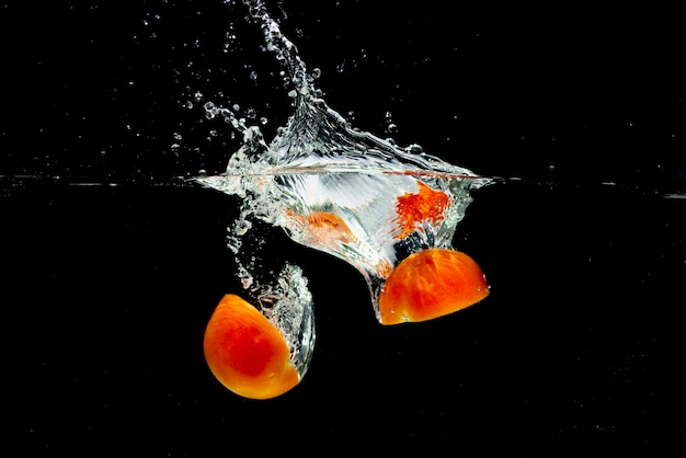 Red tomatoes halves splashing into fresh water