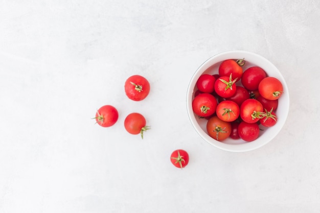 Free photo red tomatoes in white bowl on white textured background