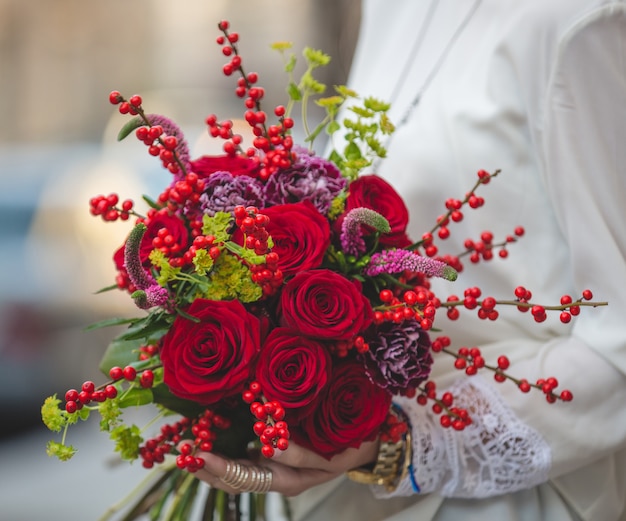 Free photo red velvet bouquet of berries , blossoms and flowers in the hands of a lady in white blouse