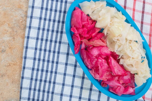 Red and white fermented cabbage on blue plate