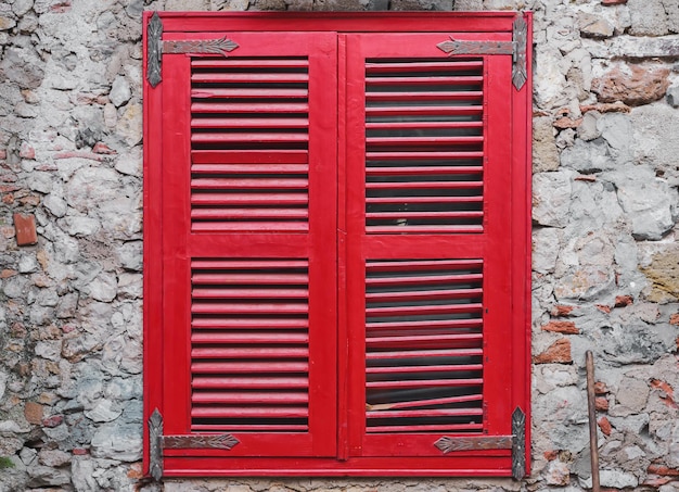 Free photo red wooden blinds close the window on the old stone wall of the house old brick wall idea for interior or loft studio and courtyard