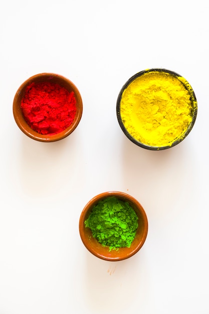 Free photo red; yellow and green holi color powder in the bowls on white background