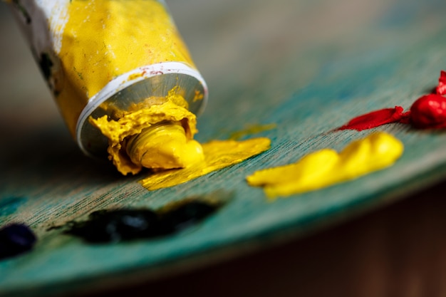 Free photo red and yellow oil paints on palette over wood wall