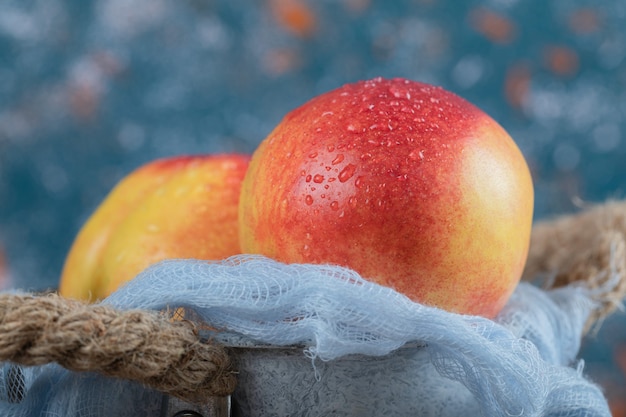 Free Photo red yellow peaches in a blue metallic bucket.