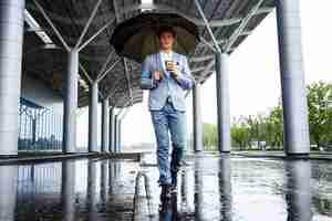 Free photo redhaired businessman with umbrella drinking coffee