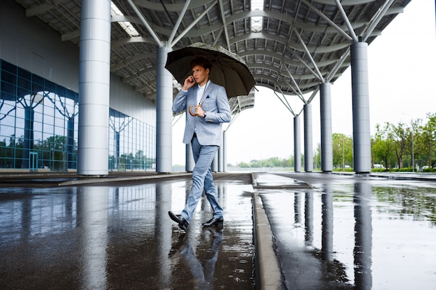 Free Photo redhaired businessman with umbrella talking on phone