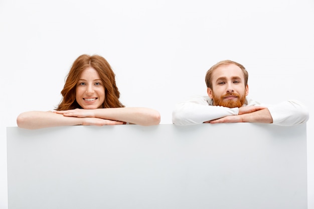 Free Photo redhead couple hiding behind table, smiling