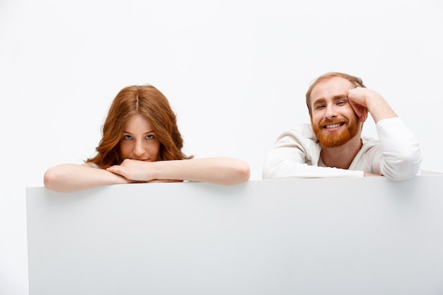 Free Photo redhead couple hiding behind table, smiling