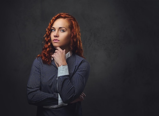 Free photo redhead female supervisor dressed in an elegant suit over grey background.