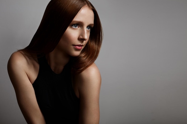 Free photo redhead girl with a blue eyes on a grey background