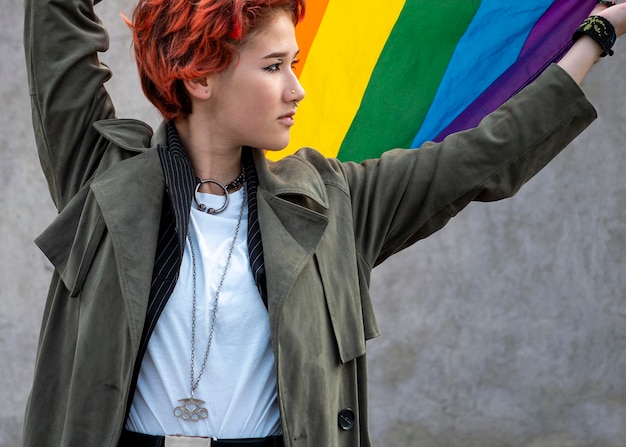 Free photo redhead non binary person holding an lgbt flag