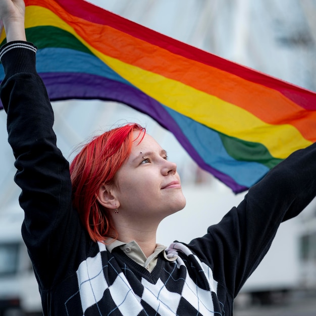 Free photo redhead non binary person holding up a lgbt flag