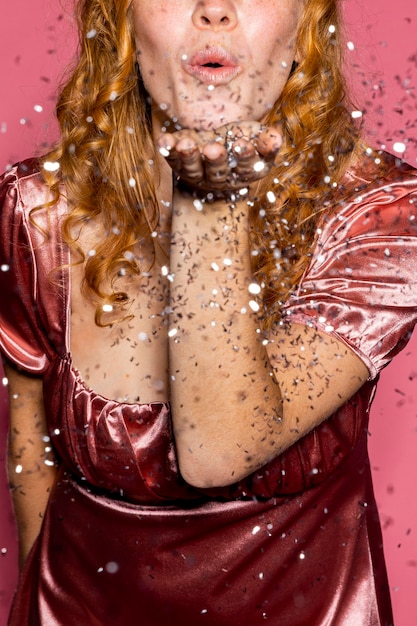 Free photo redhead woman blowing shiny confetti