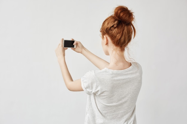 Free photo redhead woman holding phone standing back.