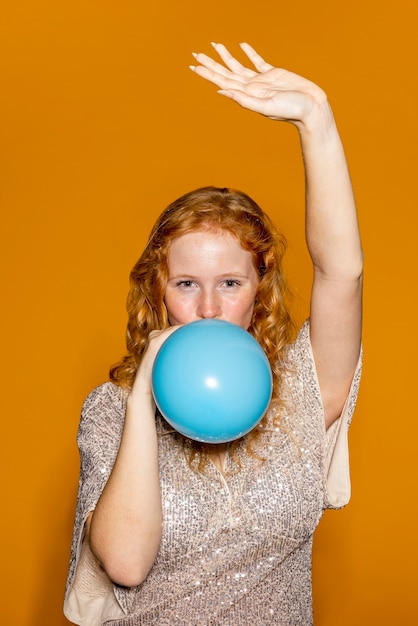 Free photo redhead woman inflating a blue balloon