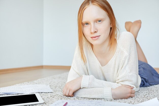 Redhead woman lying on floor with notebook and tablet