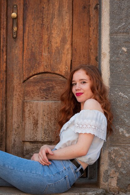 Redhead woman posing in front of a door