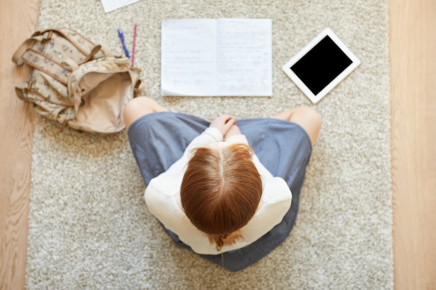 Free Photo redhead woman sitting on floor with notebook and tablet