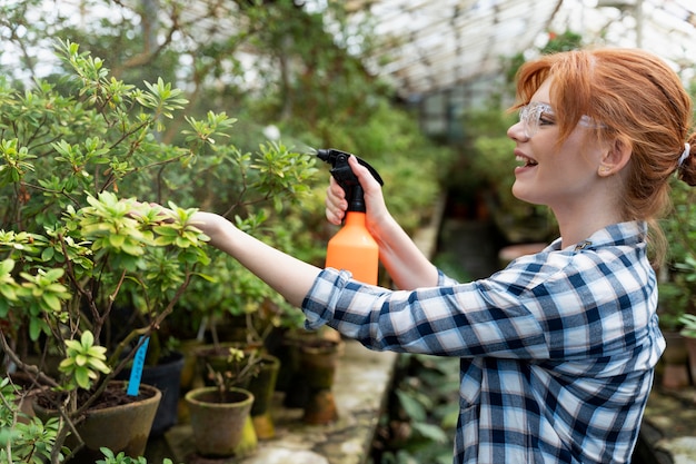 Free photo redhead woman taking care of her plants in a greenhouse