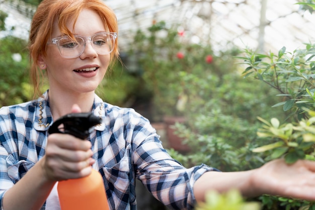 Redhead woman taking care of her plants in a greenhouse