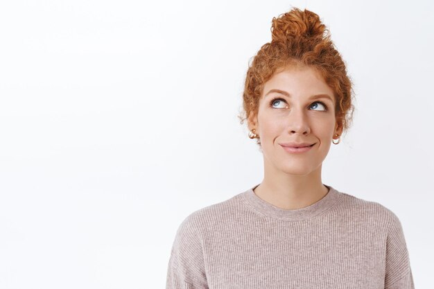 redhead woman with curly hair combed in messy bun, smiling on white