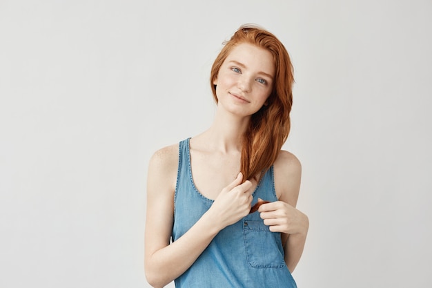 Free photo redhead woman with freckles smiling touching hair.