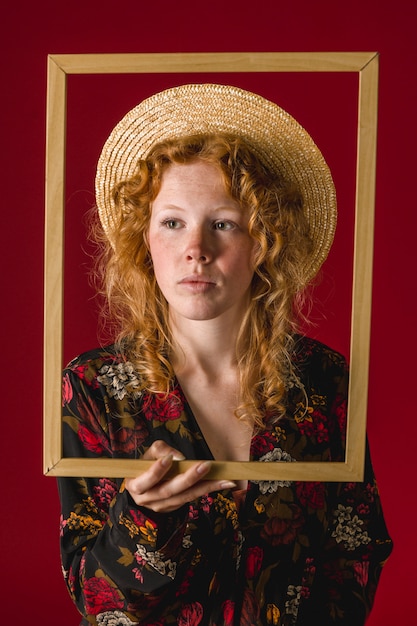 Free Photo redhead young female holding wooden frame