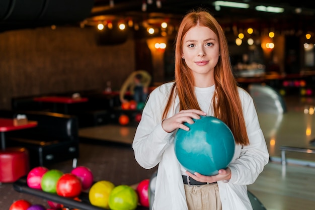 Redhead young woman holding a turquoise bowling ball