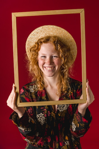 Free Photo redhead young woman smiling and holding wooden frame