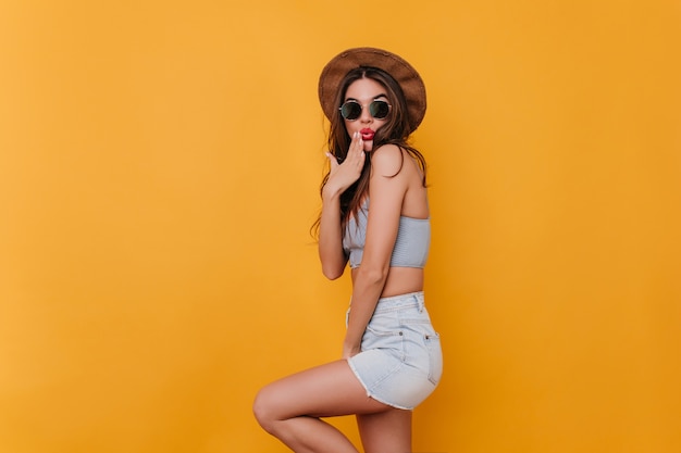 Refined shapely girl wears blue denim shorts playfully posing 