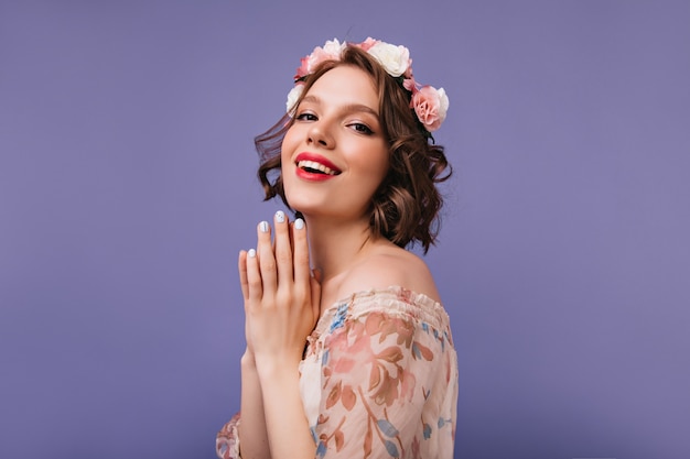 Refined white female model in romantic outfit laughing. Debonair short-haired girl with flowers on her head smiling.