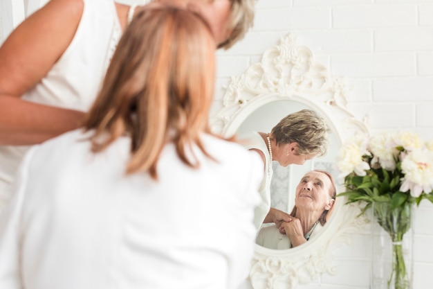 Free Photo reflection of mother and daughter on mirror at home