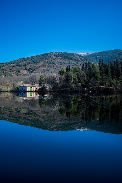 Free photo reflection of trees and hills on a lake under the sunlight and a blue sky