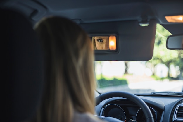 Reflection of a woman in rear view mirror of car