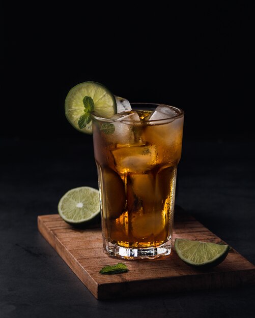 Refreshing soft drink with lime slices in glass cup over black