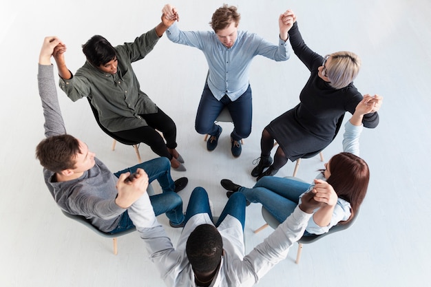 Free photo rehab patients standing in circle and raising hands