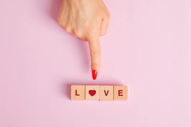 Free photo relationship concept flat lay. finger showing wooden letter cubes.