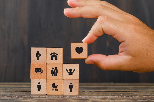 Free Photo relationship concept on wooden table side view. hand holding wooden cube with heart icon.