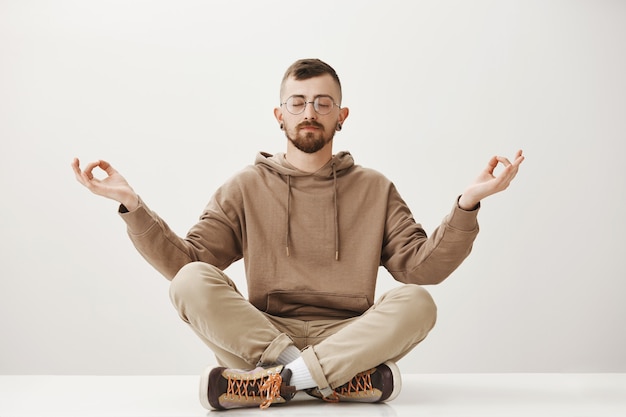 Free Photo relaxed peaceful hipster guy sit on floor and meditating, keep calm