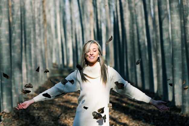 Free photo relaxed woman playing with leaves in the park