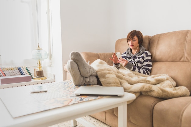 Free photo relaxed woman using her cell phone at home