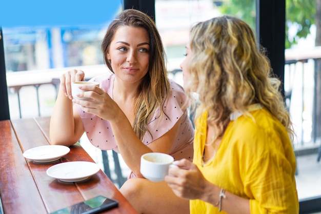 Relaxed women chatting and drinking coffee in cafe