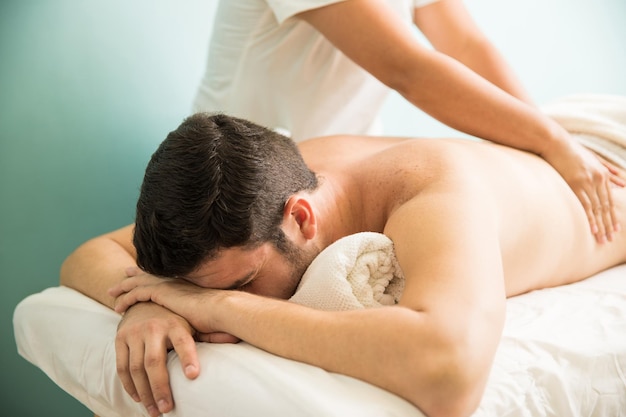 Relaxed young man getting a massage at a wellness and spa clinic