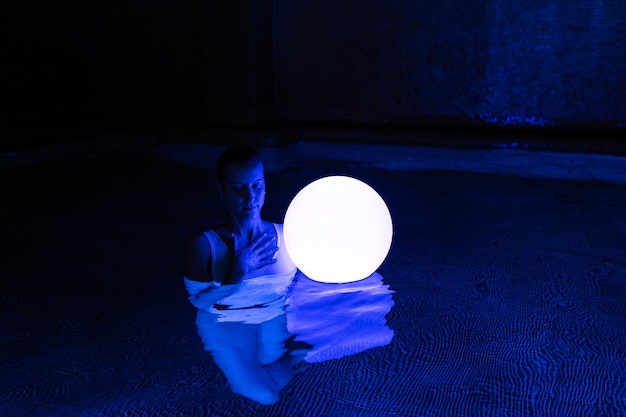 Free photo relaxed young woman in pool with neon light